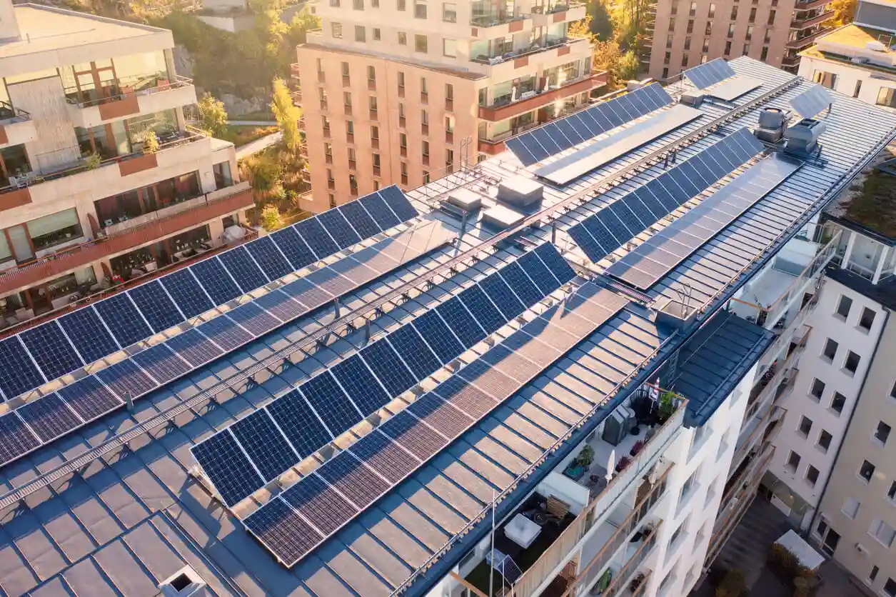 Painel solar instalado no telhado de um prédio residencial em uma área urbana, promovendo energia sustentável e economia de energia.