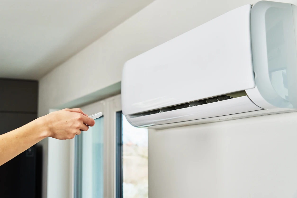 Pessoa ajustando o ar-condicionado em ambiente interno para melhorar o clima e o conforto térmico