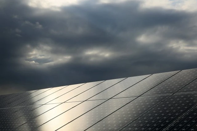 Painel de painéis solares sob céu nublado, destacando energia solar sustentável em investimento ecológico.